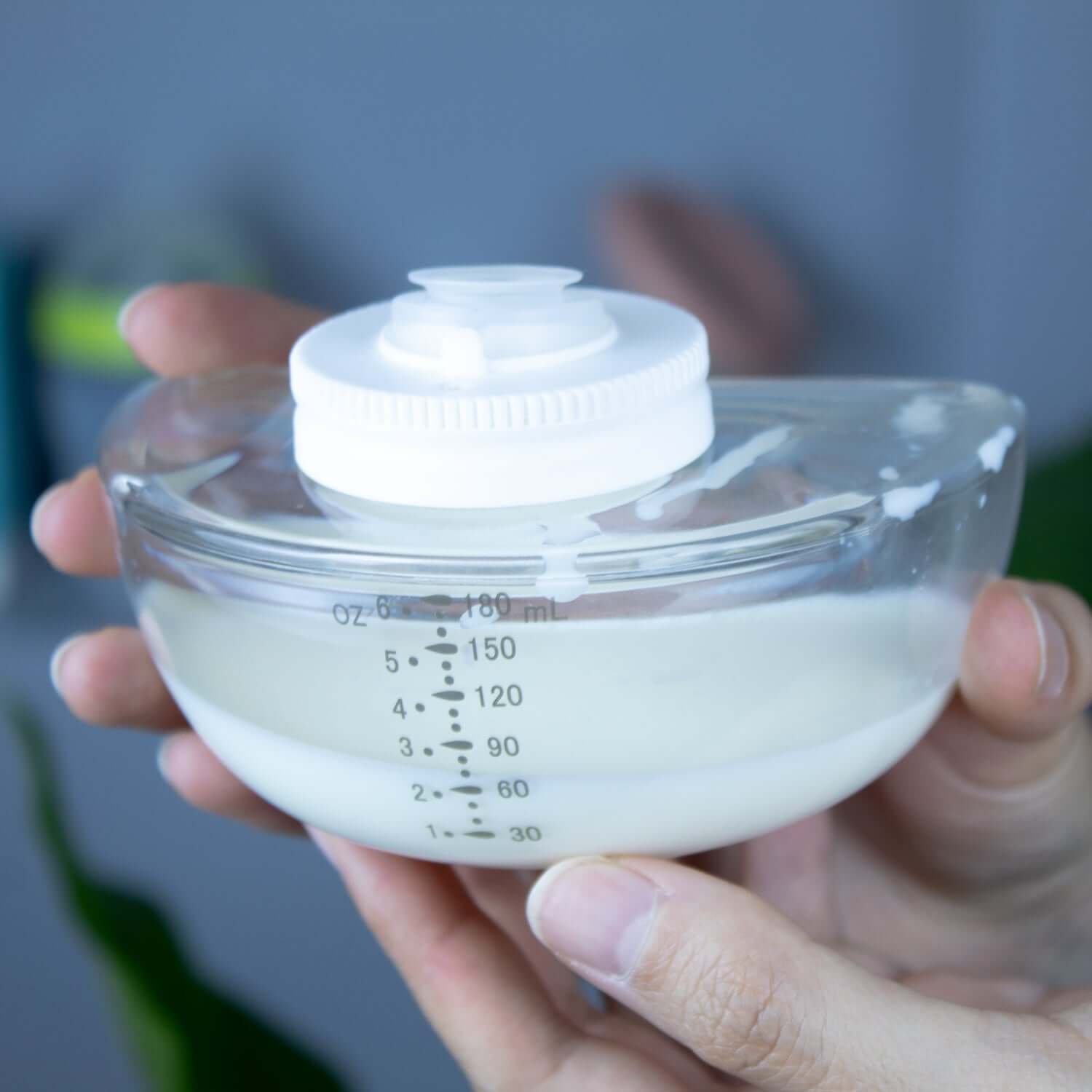 Extractor de leche inalámbrico Balia en un recipiente transparente con escala de medición.